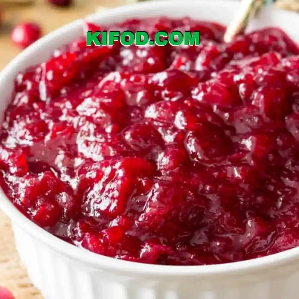 Homemade cranberry sauce in a bowl with fresh cranberries and herbs