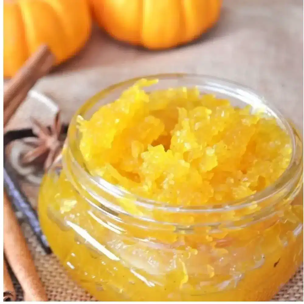 Jar of fresh pumpkin jam with cinnamon and cloves on a wooden table