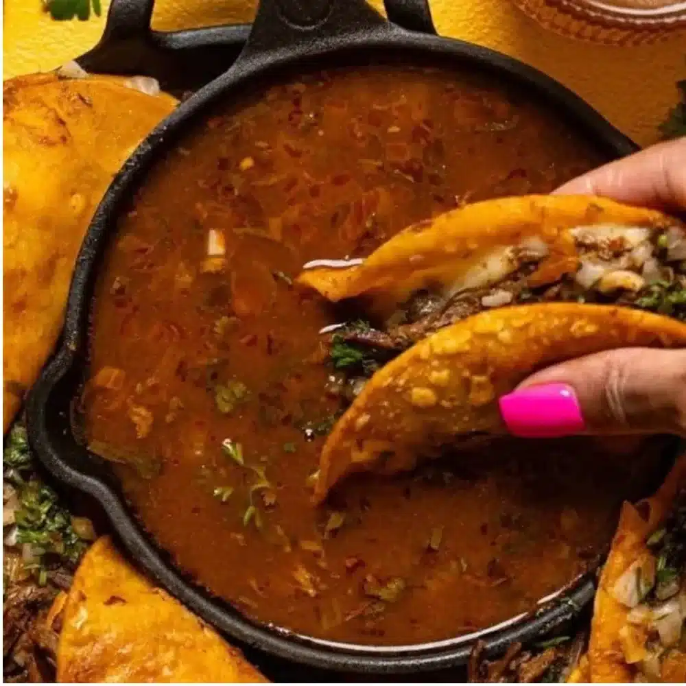 Delicious birria tacos served with consommé and fresh toppings