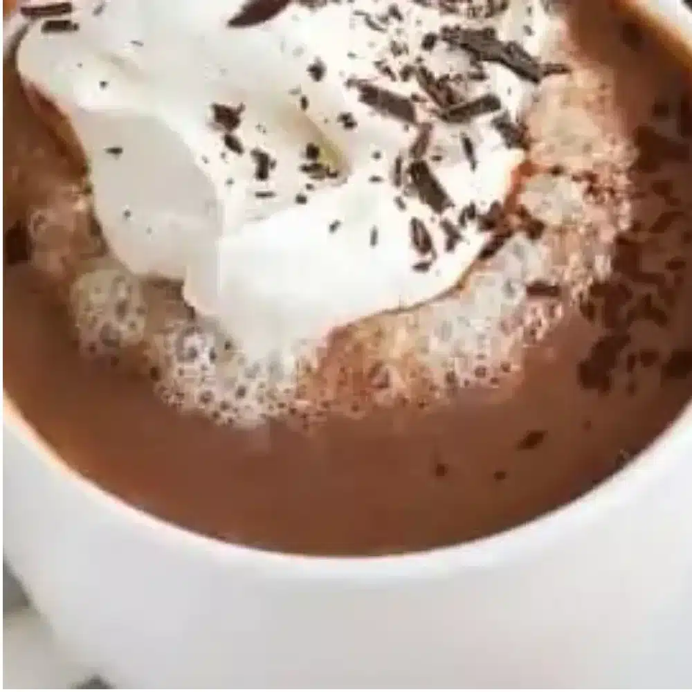 A cup of rich French hot chocolate topped with whipped cream and chocolate shavings