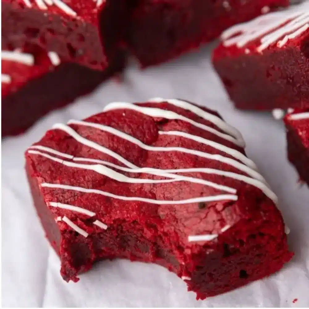 Fudgy red velvet brownies with cream cheese frosting on a wooden table