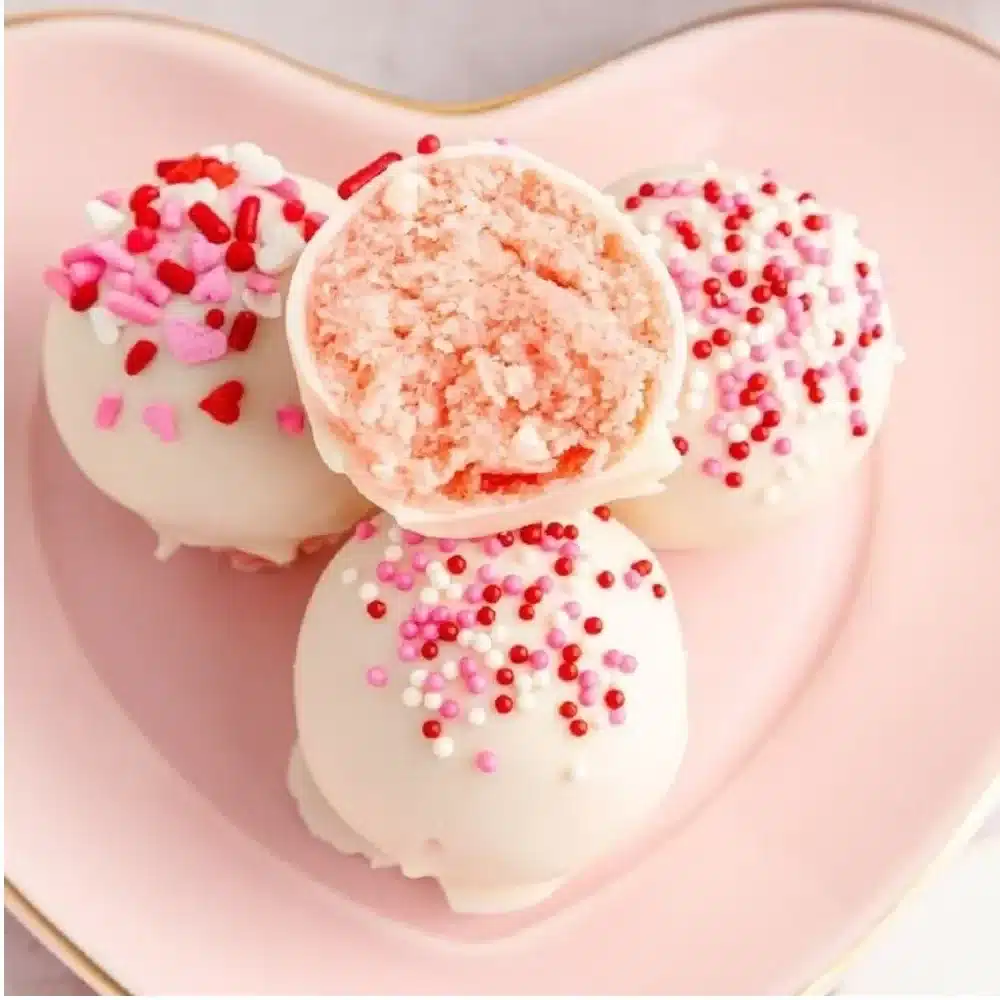 Delicious strawberry cake truffles coated in white chocolate and topped with sprinkles