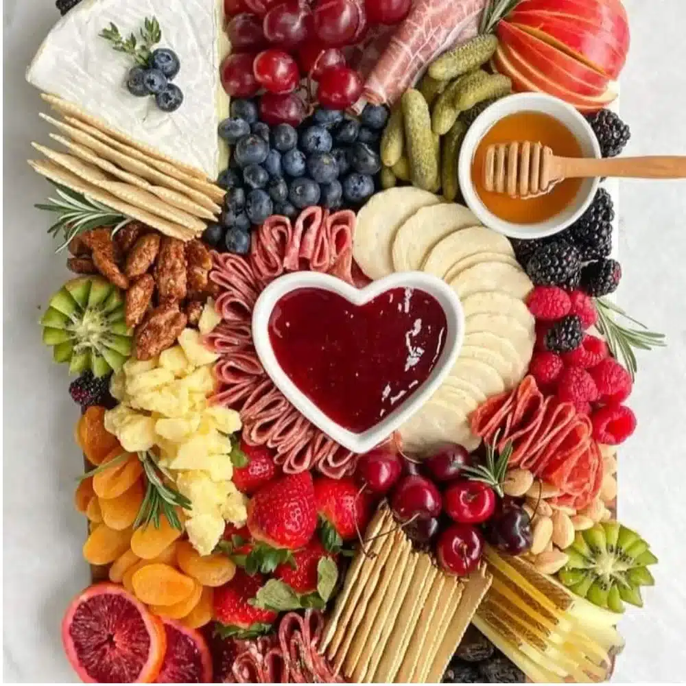 A beautifully arranged Valentine's Day charcuterie board with cheeses, meats, and heart-shaped treats.