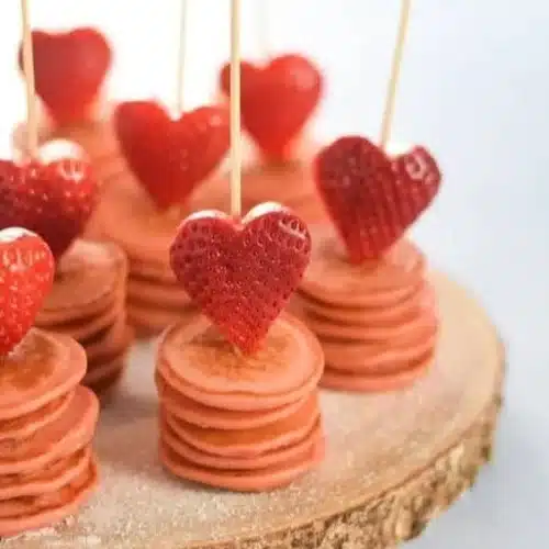 Cute Valentine's Day breakfast featuring heart-shaped pancakes and fresh berries.