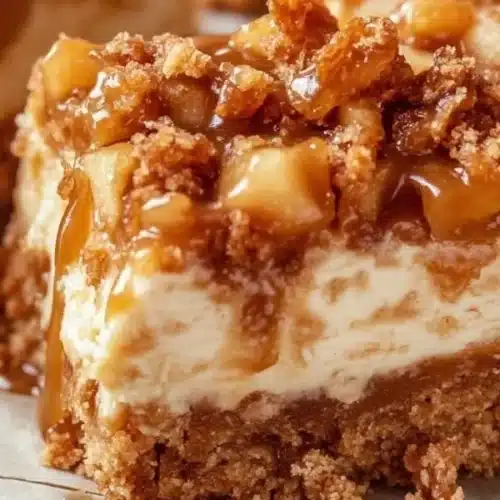 Delicious caramel apple cheesecake bars garnished with caramel drizzle and apple slices.