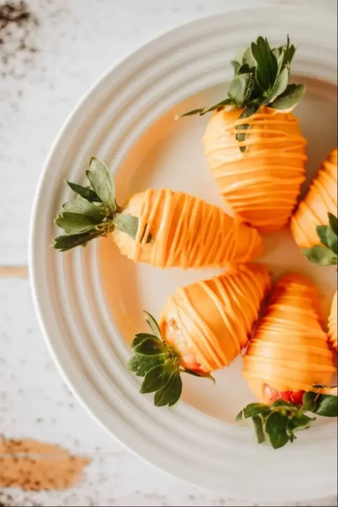 Easter chocolate covered strawberry carrots arranged on a festive plate.