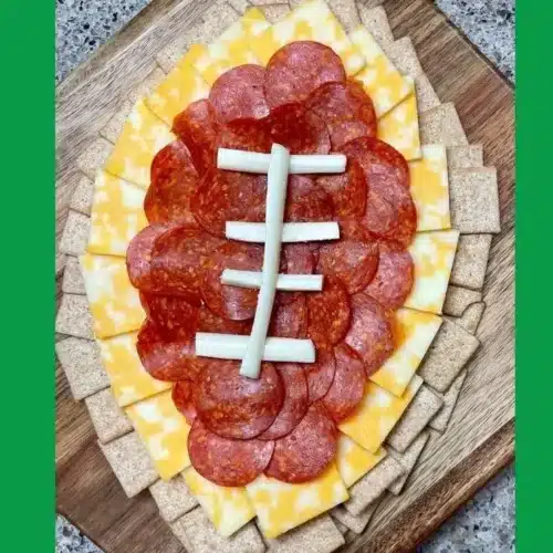 Delicious football charcuterie board with meats, cheeses, and snacks for game day.