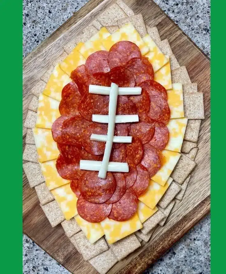 Delicious football charcuterie board with meats, cheeses, and snacks for game day.