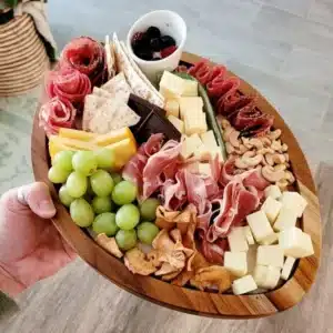 Football shaped charcuterie board filled with assorted meats and cheeses.