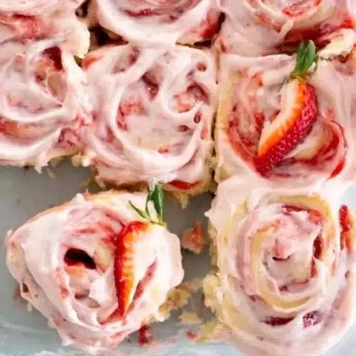 Freshly baked strawberry cinnamon rolls topped with icing and strawberries